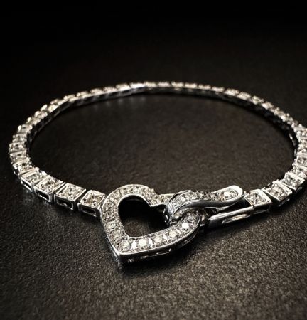 Brazalete de tenis en oro blanco con cierre de corazón.